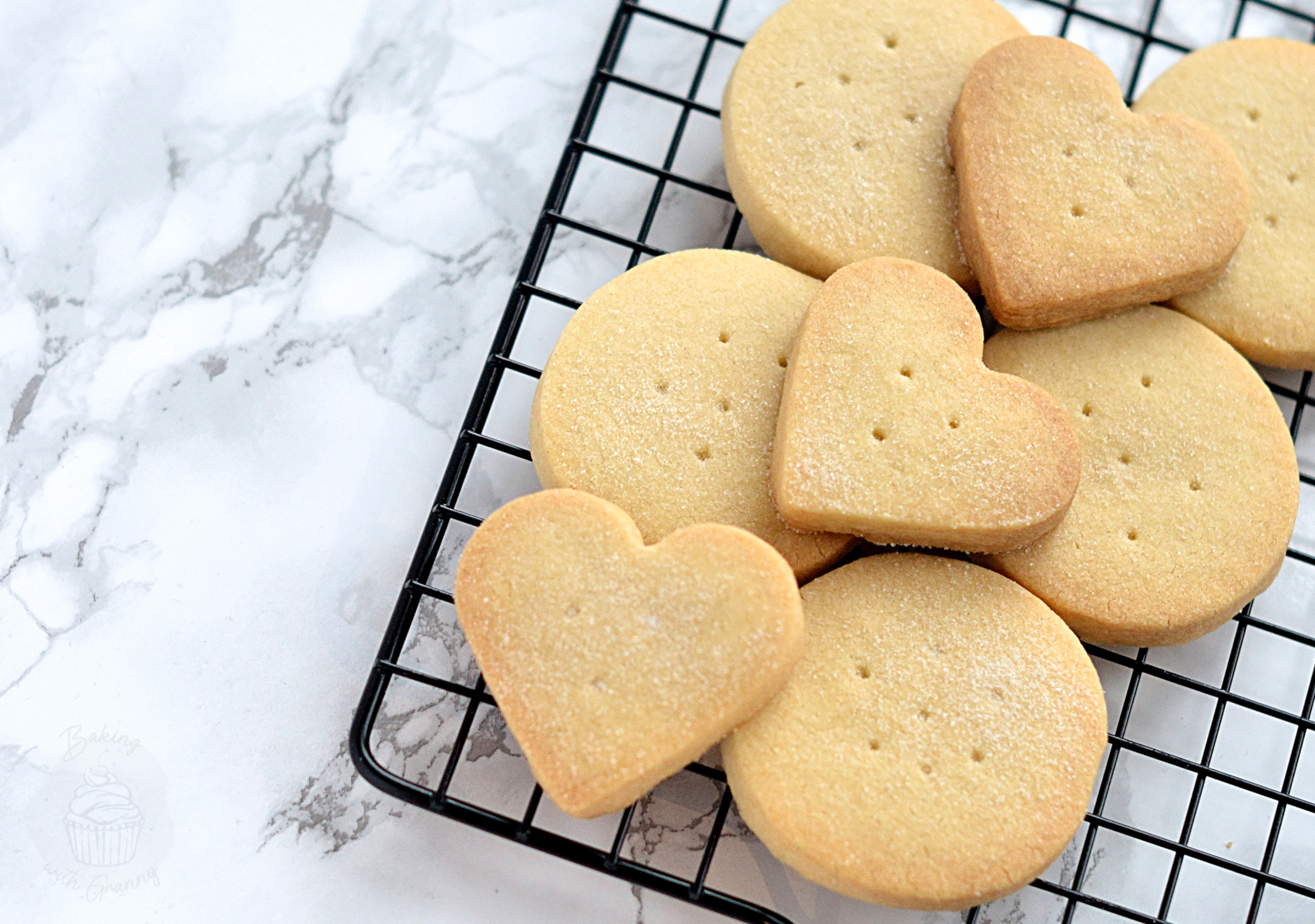 Round and heart-shaped shortbread biscuits cooling on a wire rack.