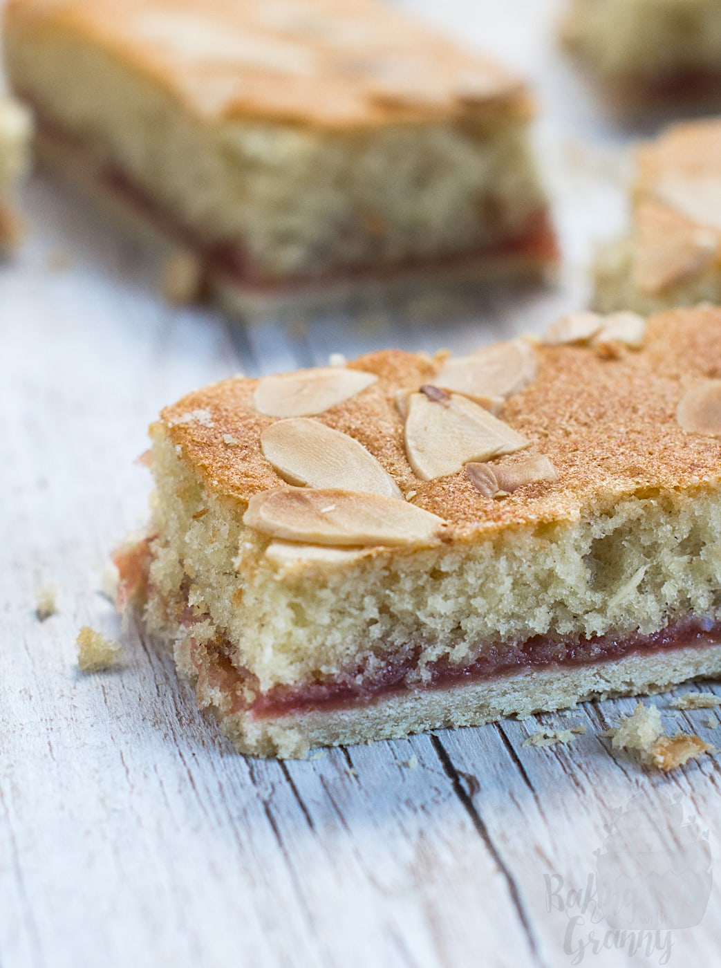 Almond Slice close-ip, showing the pastry bottom, raspberry jam filling and almond sponge, topped with flaked almonds.