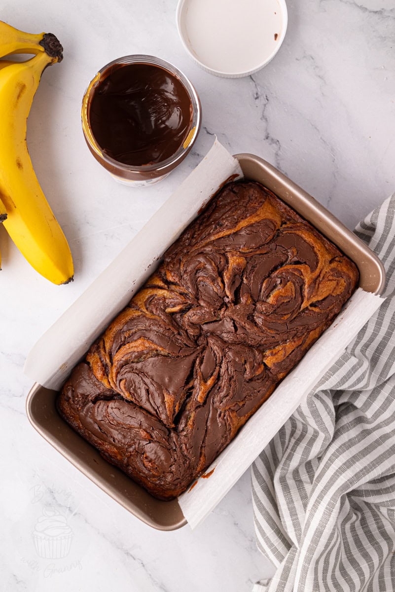 Banana Nutella loaf cake baked in a loaf tin with chocolate hazelnut swirl topping.