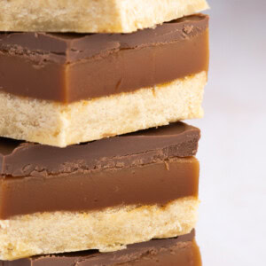 Stacked slices of Millionaires Shortbread with defined layers of shortbread base, thick caramel centre, and chocolate topping.