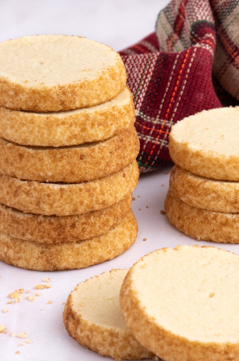 Stack of Highlander Shortbread biscuits coated in demerara sugar, with a tartan cloth in the background.