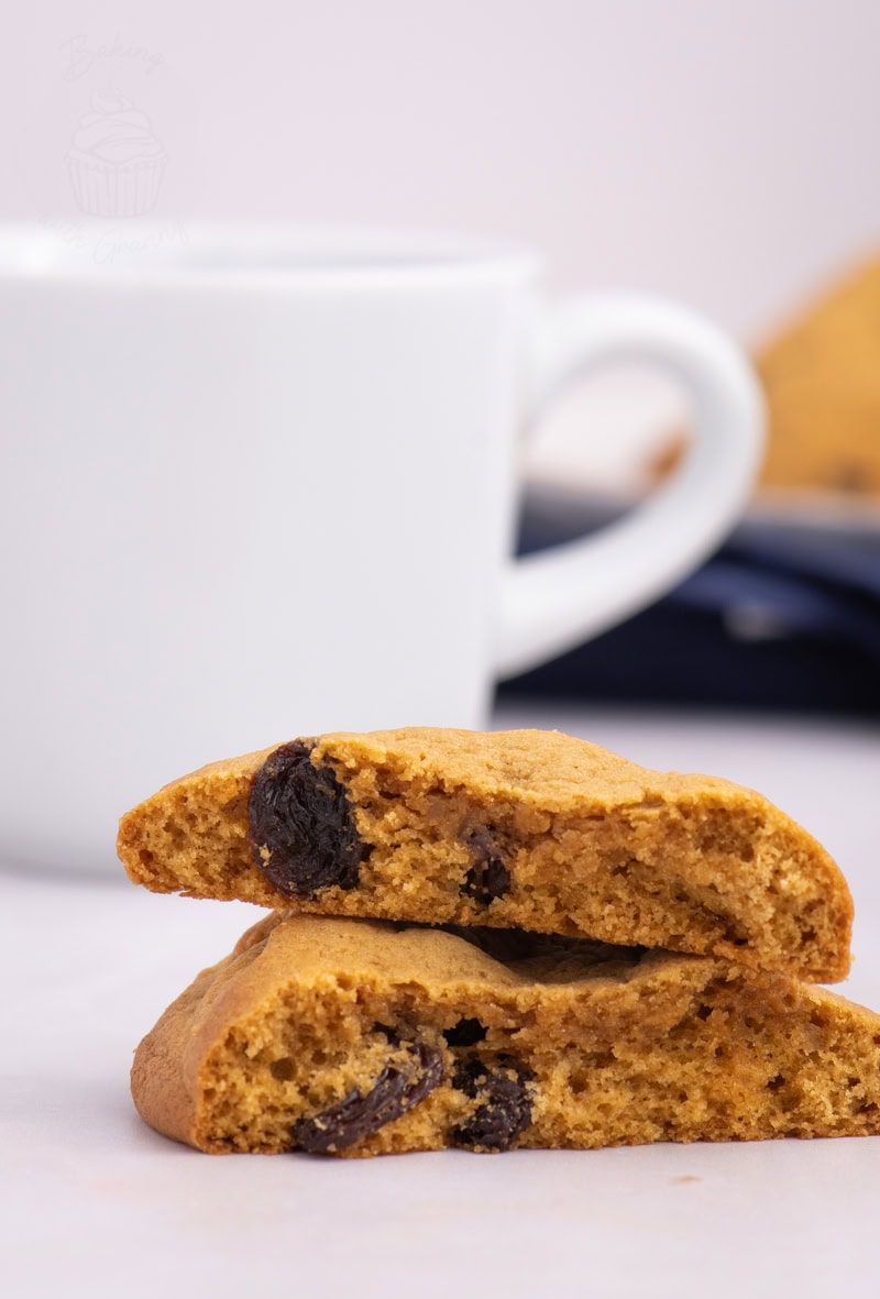 Coffee Bun with sultanas, halved and stacked, served alongside a white coffee cup.