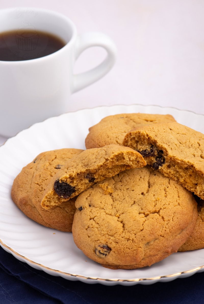 Coffee Buns on a plate, with one bun broken open to reveal raisins inside.