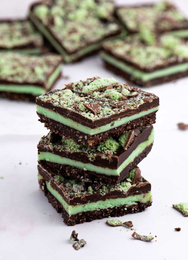 Stacked Peppermint Slice squares with biscuit base, green peppermint icing, and chocolate topping sprinkled with crushed Mint Aero.