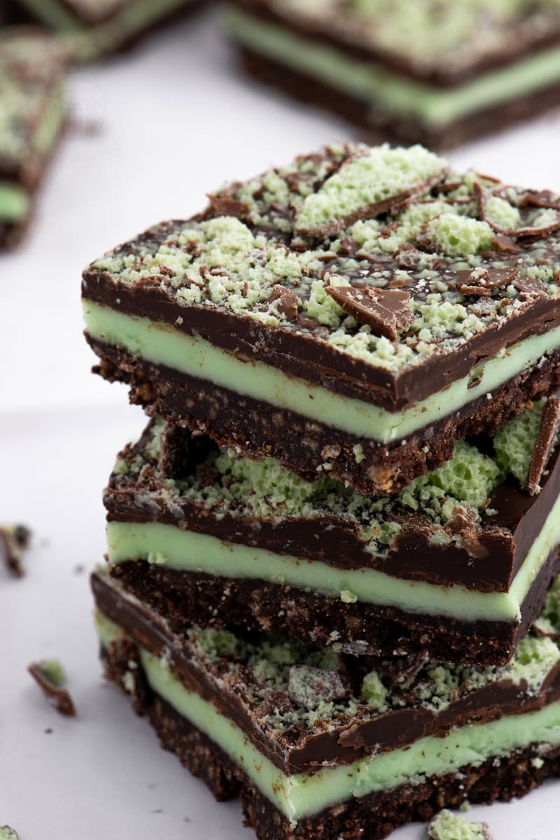 Stack of Peppermint Slice squares with crumbly biscuit base, mint green filling, and chocolate topping.