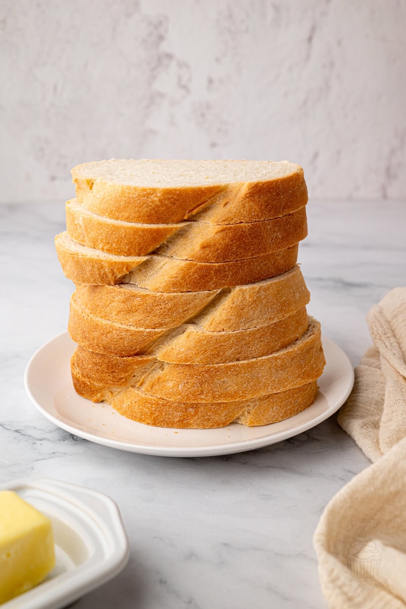 Tall stack of evenly sliced homemade white bread on a plate.