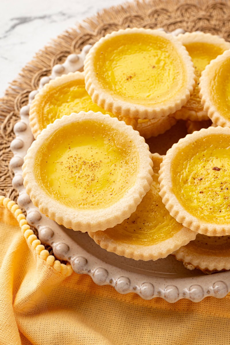 Close-up of custard tart showing detailed pastry texture and smooth, slightly glossy custard centre.