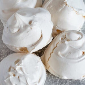 Pile of freshly baked meringues with cracked, glossy shells, part of an easy homemade meringue recipe.