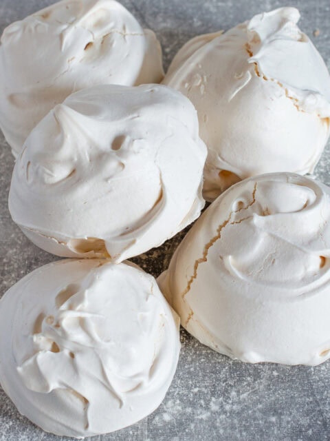 Pile of freshly baked meringues with cracked, glossy shells, part of an easy homemade meringue recipe.