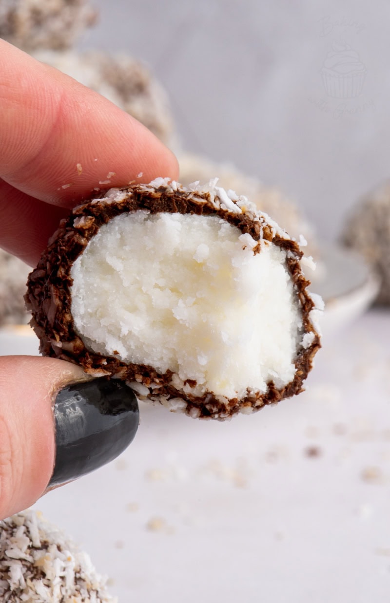 Hand holding a Scottish Macaroon, showing the fluffy potato and sugar centre coated in chocolate and coconut.