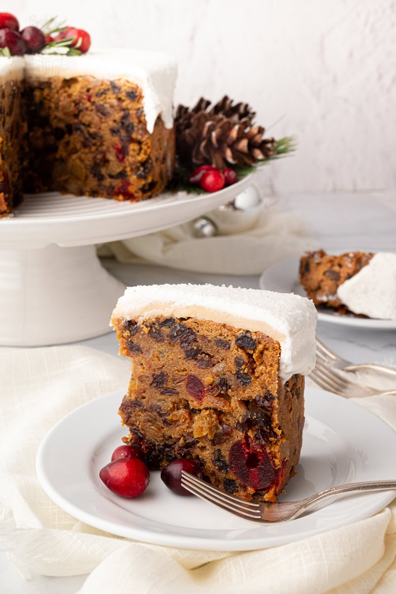 Close-up of a classic British Christmas cake topped with white icing and decorated with cranberries. Traditional UK fruit cake recipe.