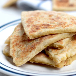 A pile of fresh tattie scones on a plate, with more behind them in the background. Made to a traditional Scottish recipe.