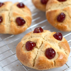 Victoria Scones on a wire rack. Freshly baked golden scones, finished with a cross and glace cherries.