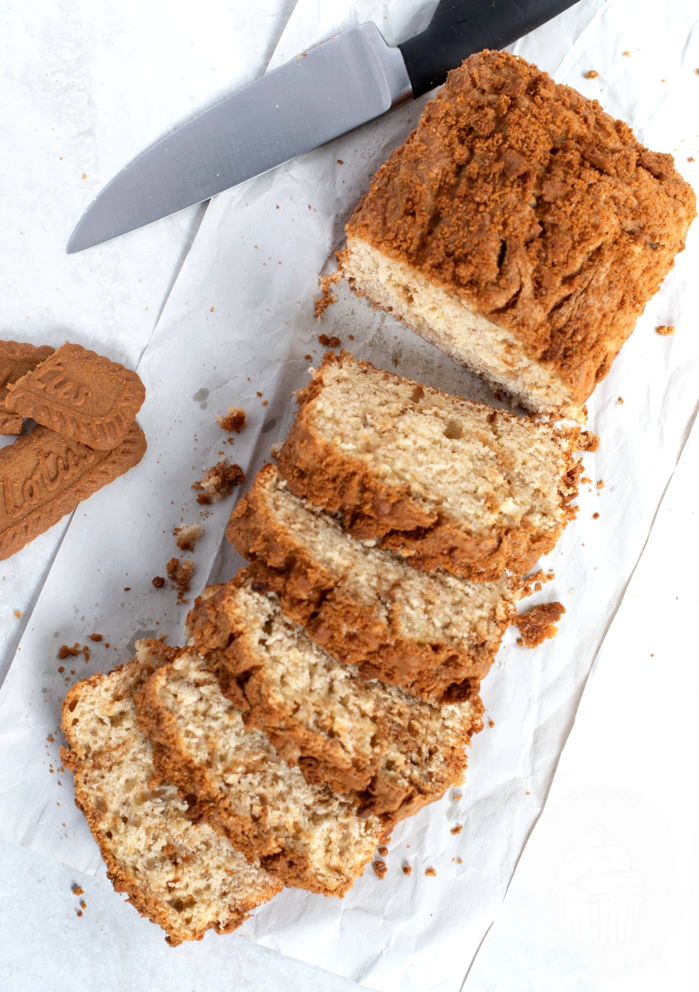 Banana Biscoff Loaf, sliced into individual portions, with Biscoff biscuits to the side and a knife for slicing beside.