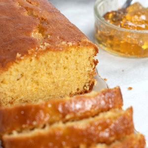 Marmalade cake loaf, sliced into individual portions, with a small jar of open marmalade in the background.