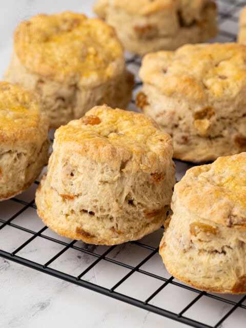 Wire rack filled with traditional Fruit Scones, with a pastry cutter in the background.
