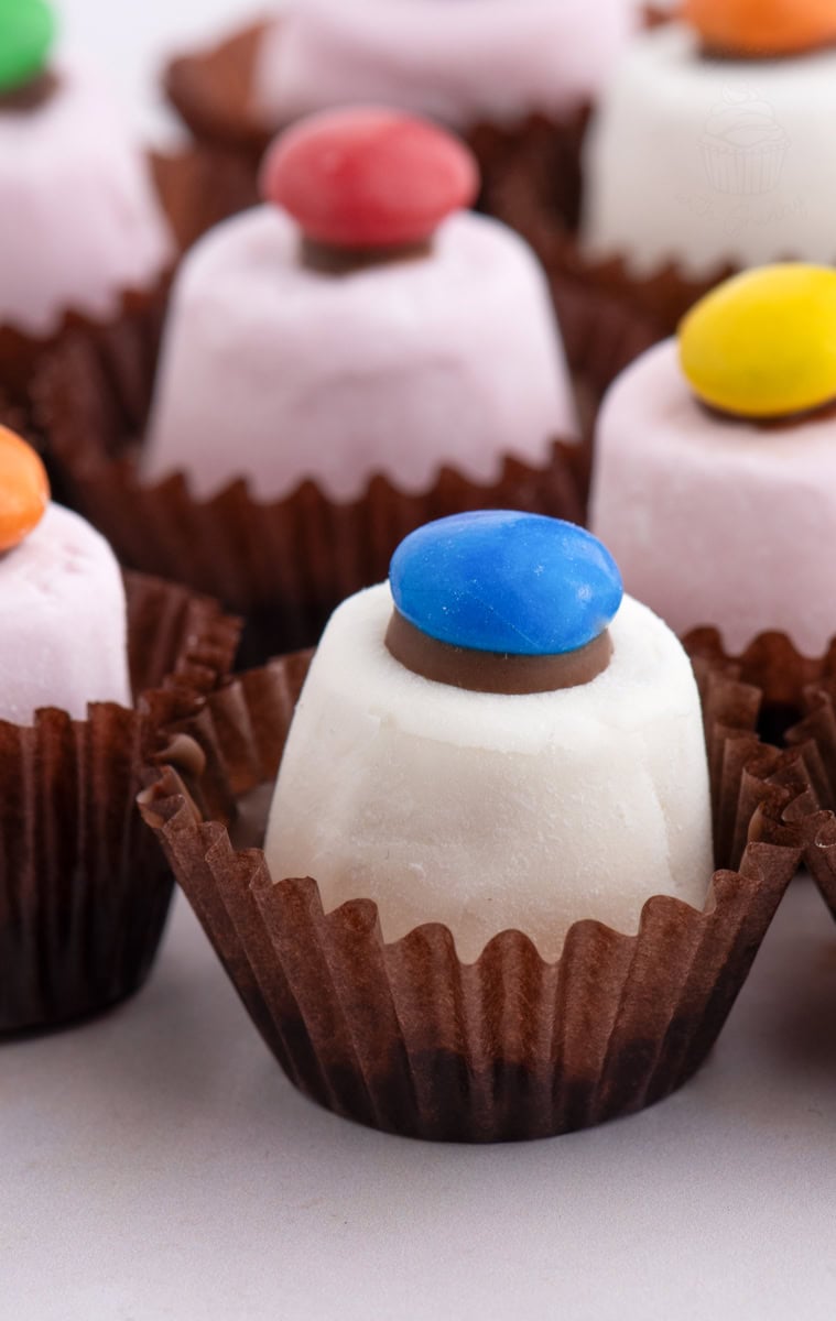 Close-up of a white Marshmallow Top Hat topped with a blue smartie, in a brown case. Traditional treat found at children's birthday parties in Scotland.