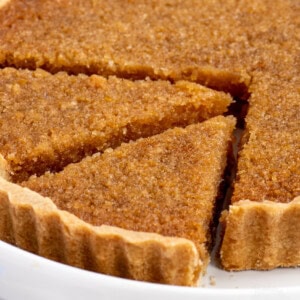 Close-up of sliced treacle tart with a crunchy golden top and syrupy centre. A traditional British bake, perfect for pudding.
