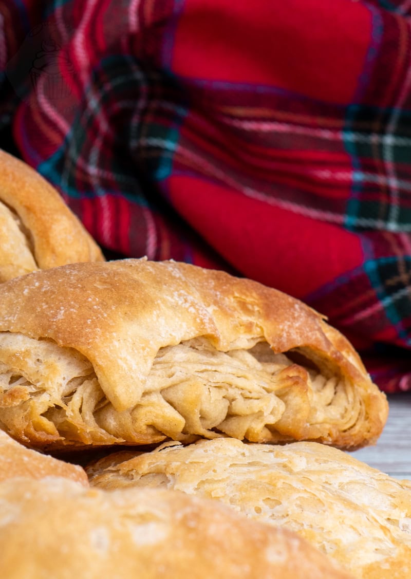 Scottish buttery (rowie) with golden, flaky layers on a wooden surface.