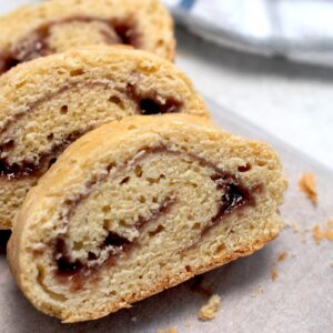 Sliced jam roly poly showing its rolled sponge and jam filling.