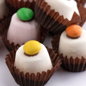 Chocolate-covered marshmallow top hats decorated with colourful sweets.