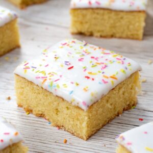 School cake topped with white icing and colourful rainbow sprinkles.