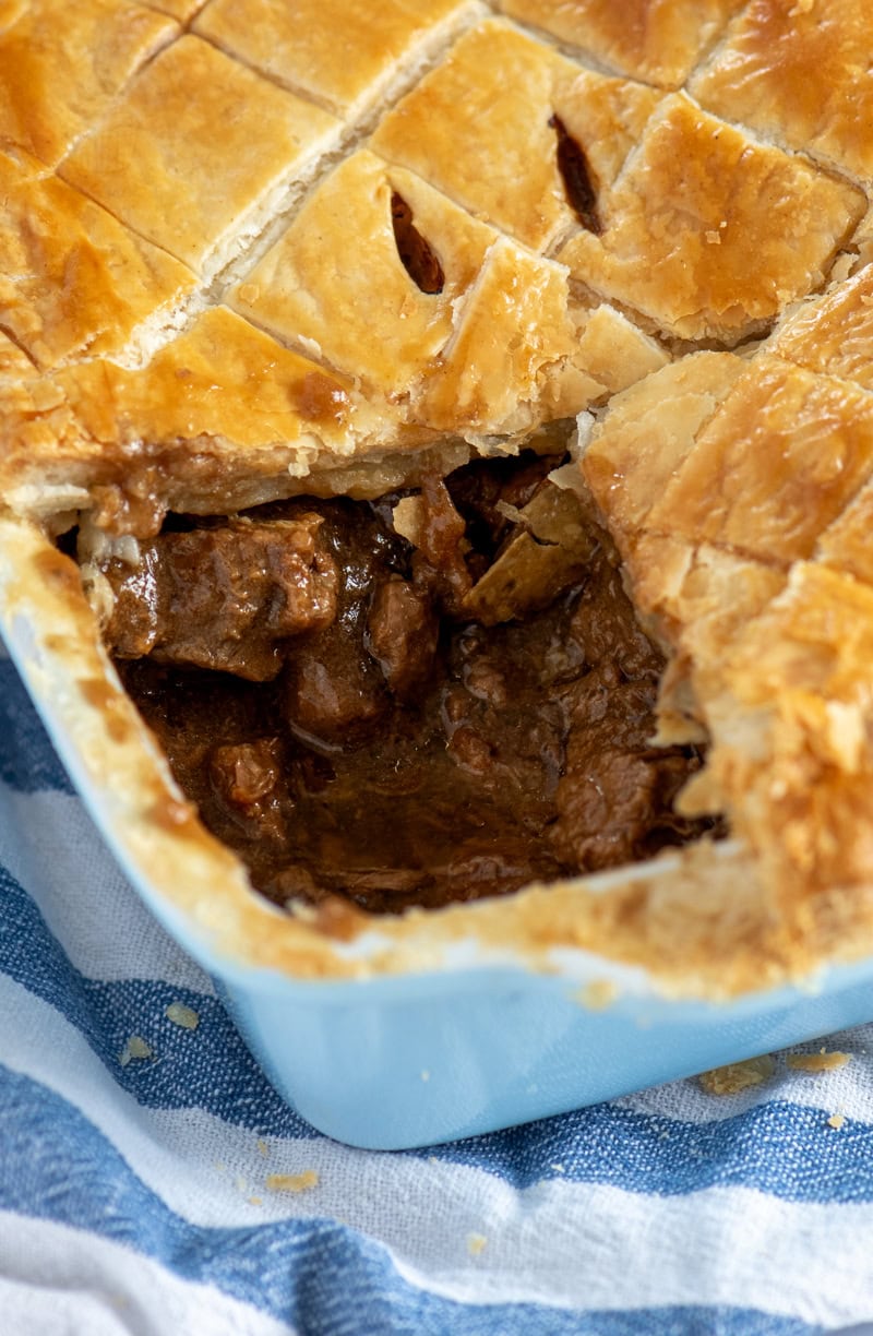 Close-up of a homemade Scottish steak pie with golden puff pastry, showing the rich beef filling inside.