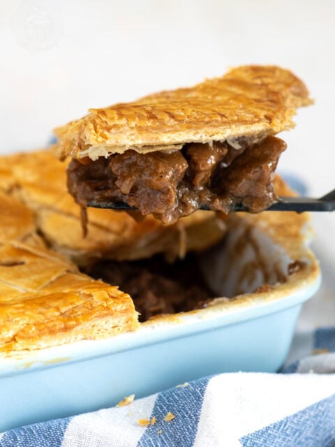 Slice of Scottish steak pie being lifted from the dish, showing chunks of beef in thick gravy.