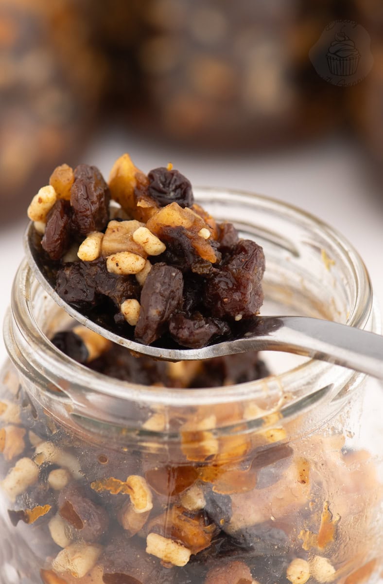 Spoonful of homemade British Christmas mincemeat being lifted from a glass jar.