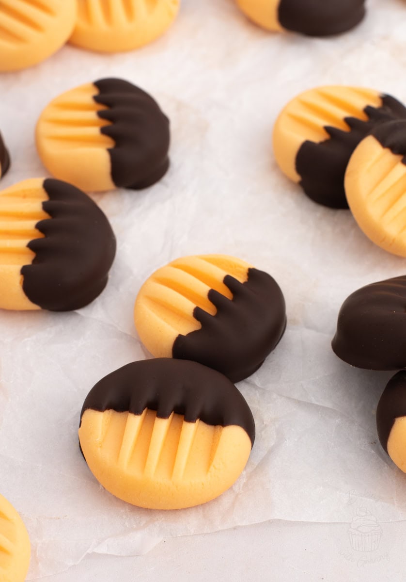 Bright orange creams with chocolate-dipped edges spread out on baking paper, classic homemade Christmas sweet.