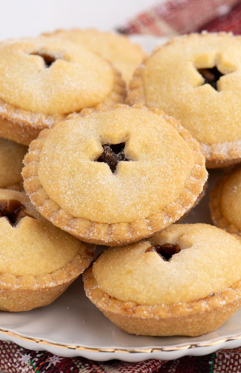 Stack of traditional mince pies with crisp, golden pastry and sugared tops, highlighting the homemade texture.