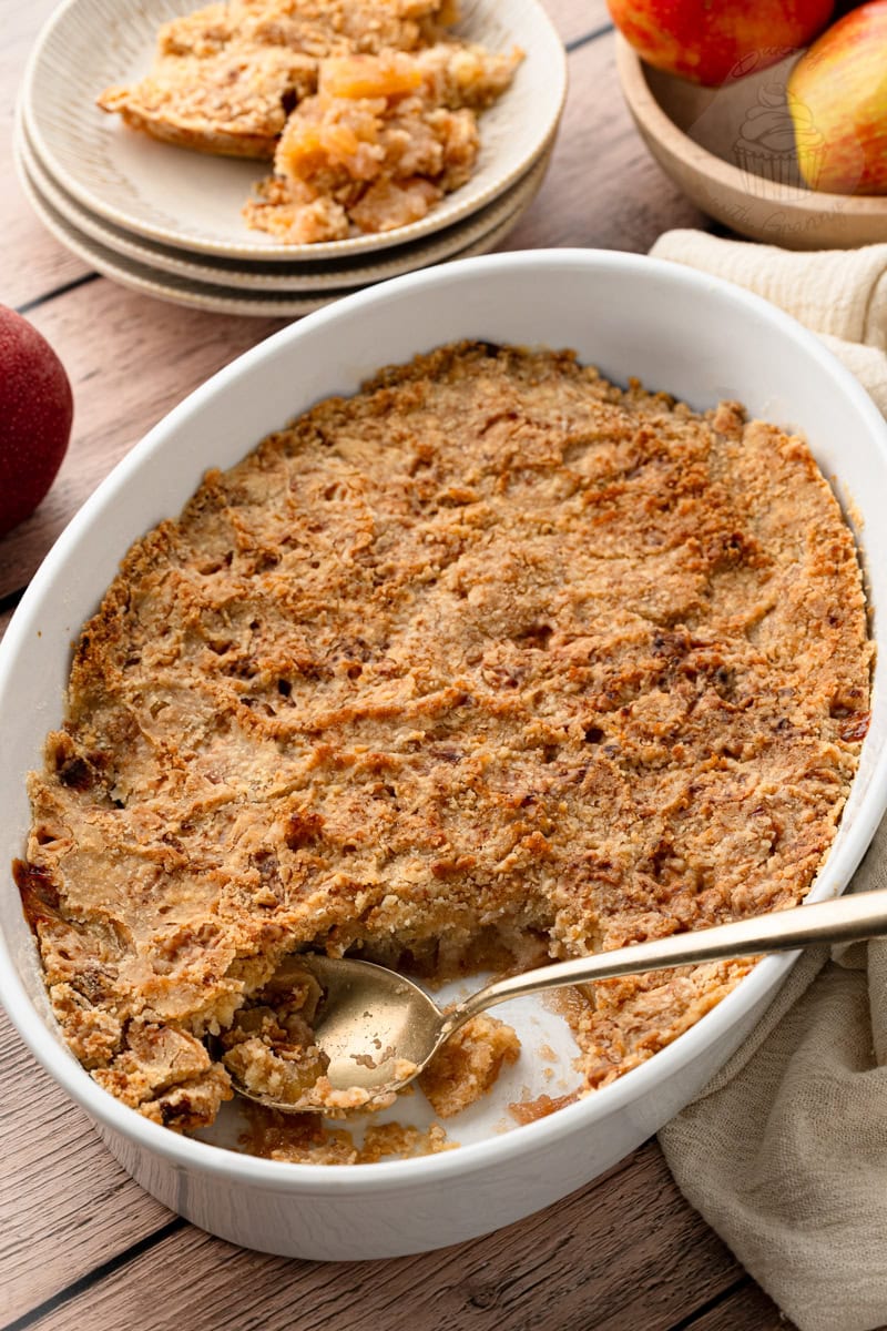An easy apple crisp recipe baked to a perfect crisp crust, showing a gold spoon scooping out a serving.