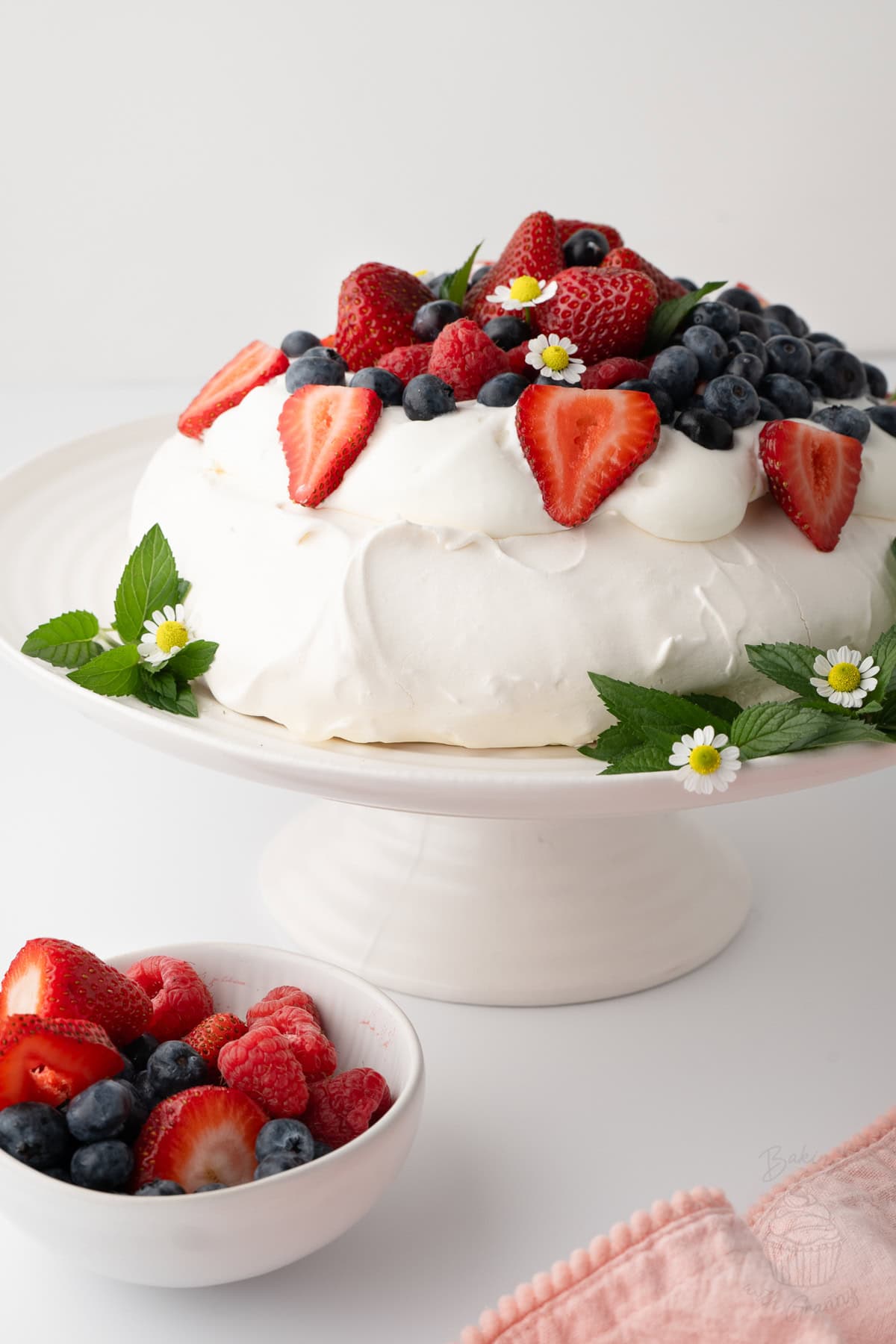 Pavlova topped with whipped cream, strawberries, raspberries and blueberries.