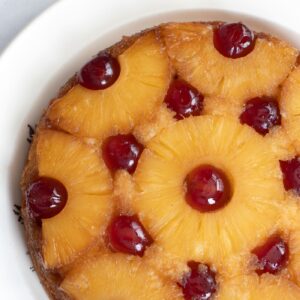 Pineapple upside-down cake topped with pineapple rings and glacé cherries.