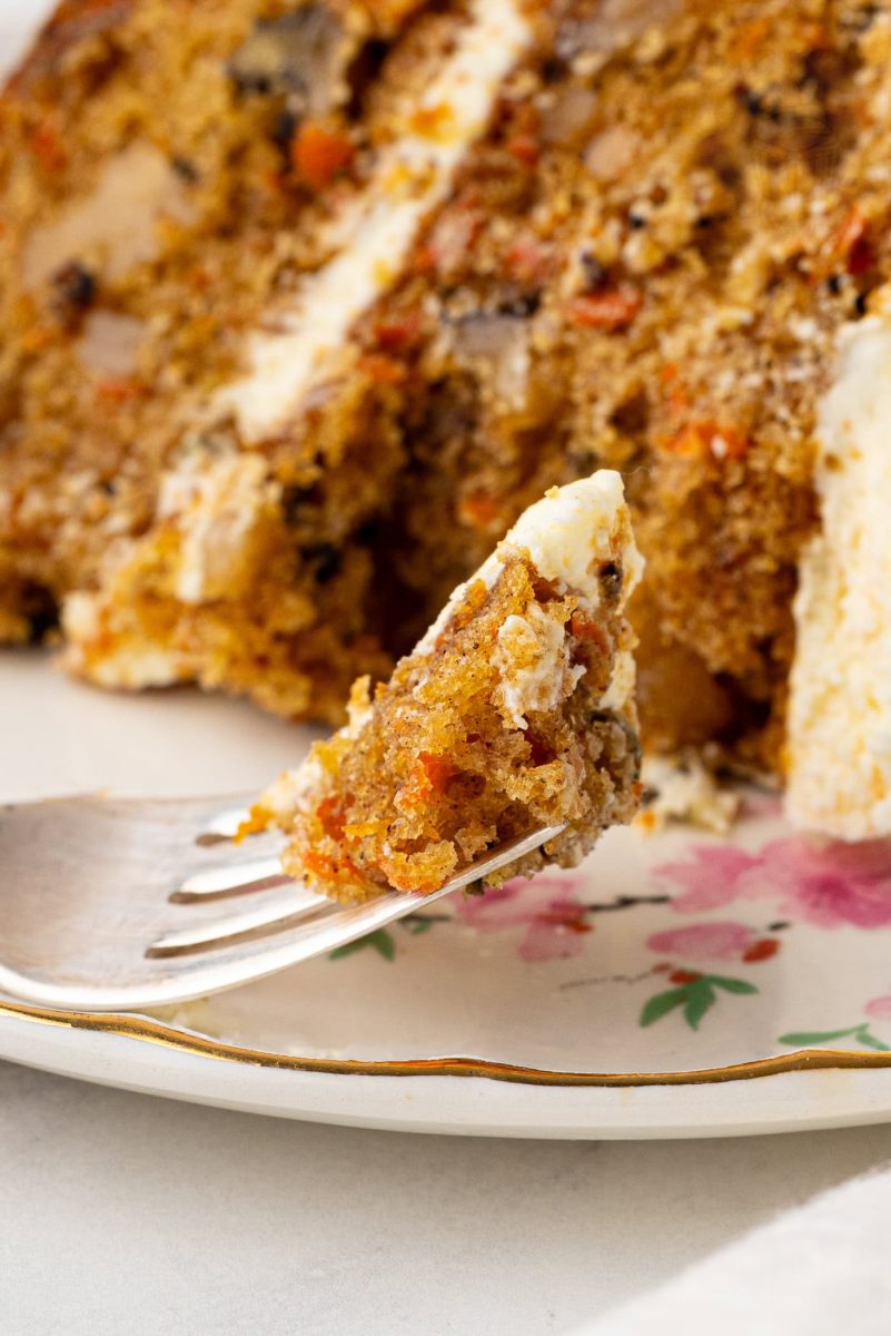 Carrot Cake Slice of carrot cake on a plate, with a fork holding up a bite, showcasing the moist crumb and pieces of walnut and carrot.