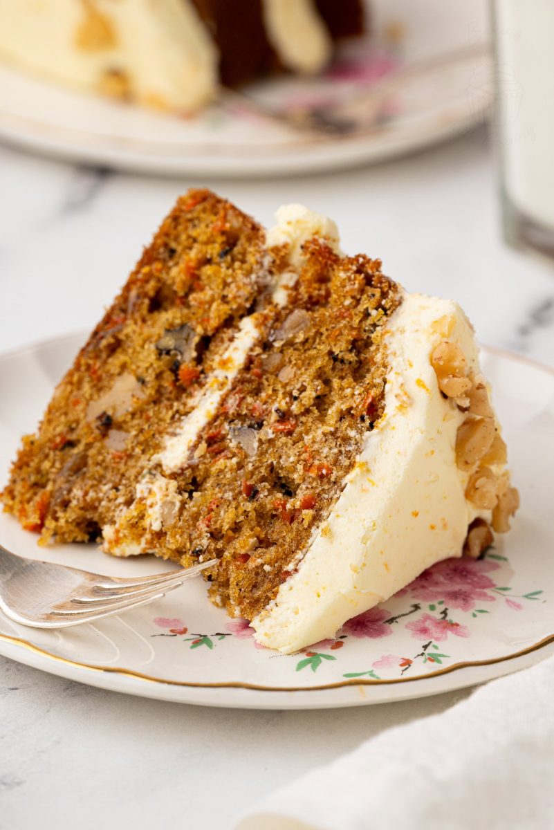 Carrot Cake Close-up of a slice of carrot cake with buttercream icing, highlighting the cake's rich texture and chunks of nuts.