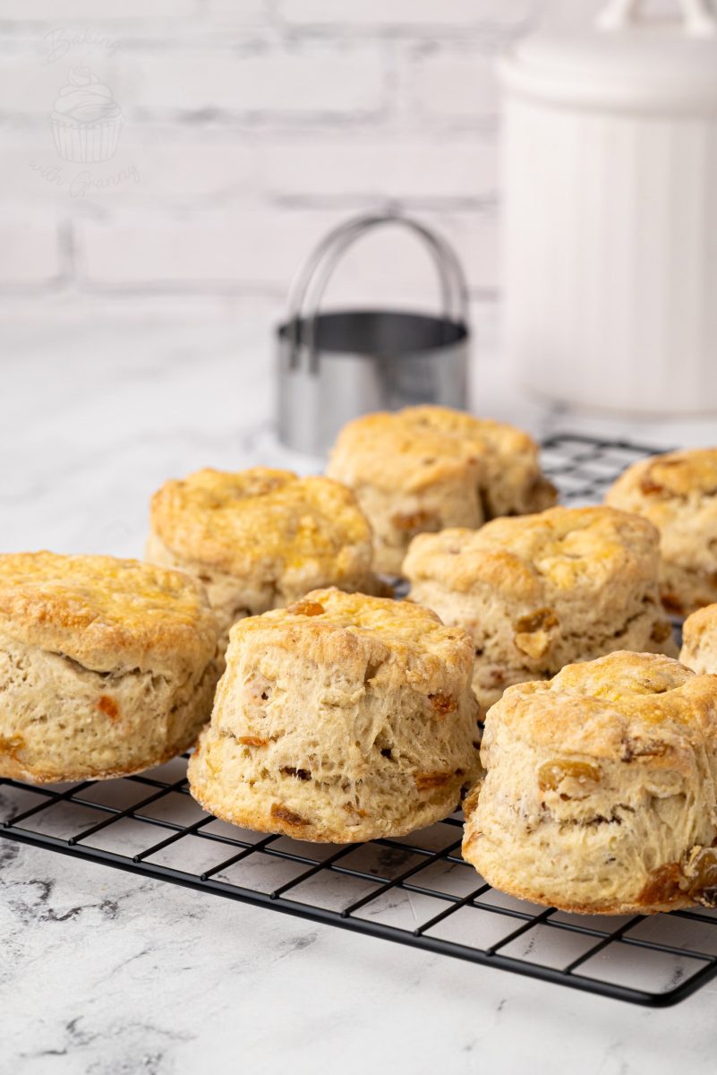 Fruit Scones Fluffy homemade Fruit Scones cooling on a wire rack, with a white sugar jar and cutter in the background.