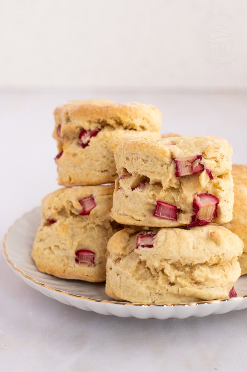 Rhubarb Scones A view of stacked homemade Rhubarb Scones on a white plate with gold rim.