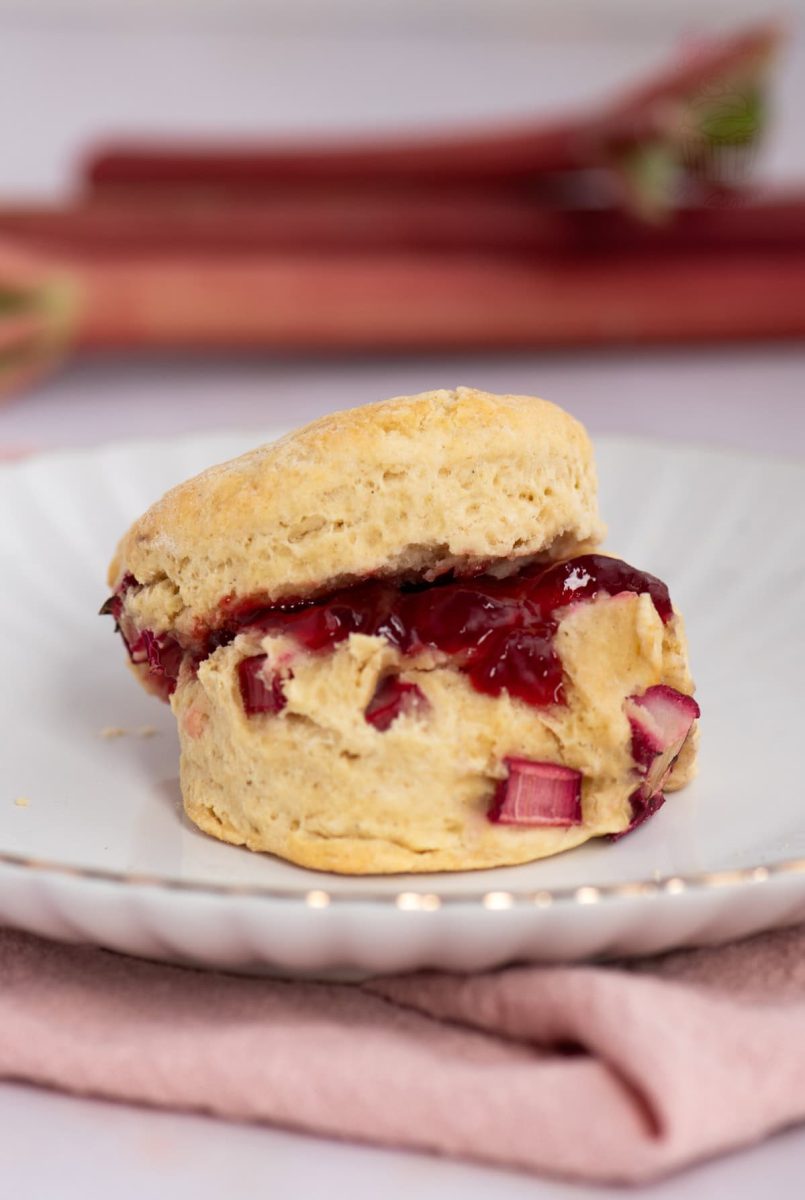 Rhubarb Scones Rhubarb Scone sliced and filled with strawberry jam, served on a white plate with pink napkin.